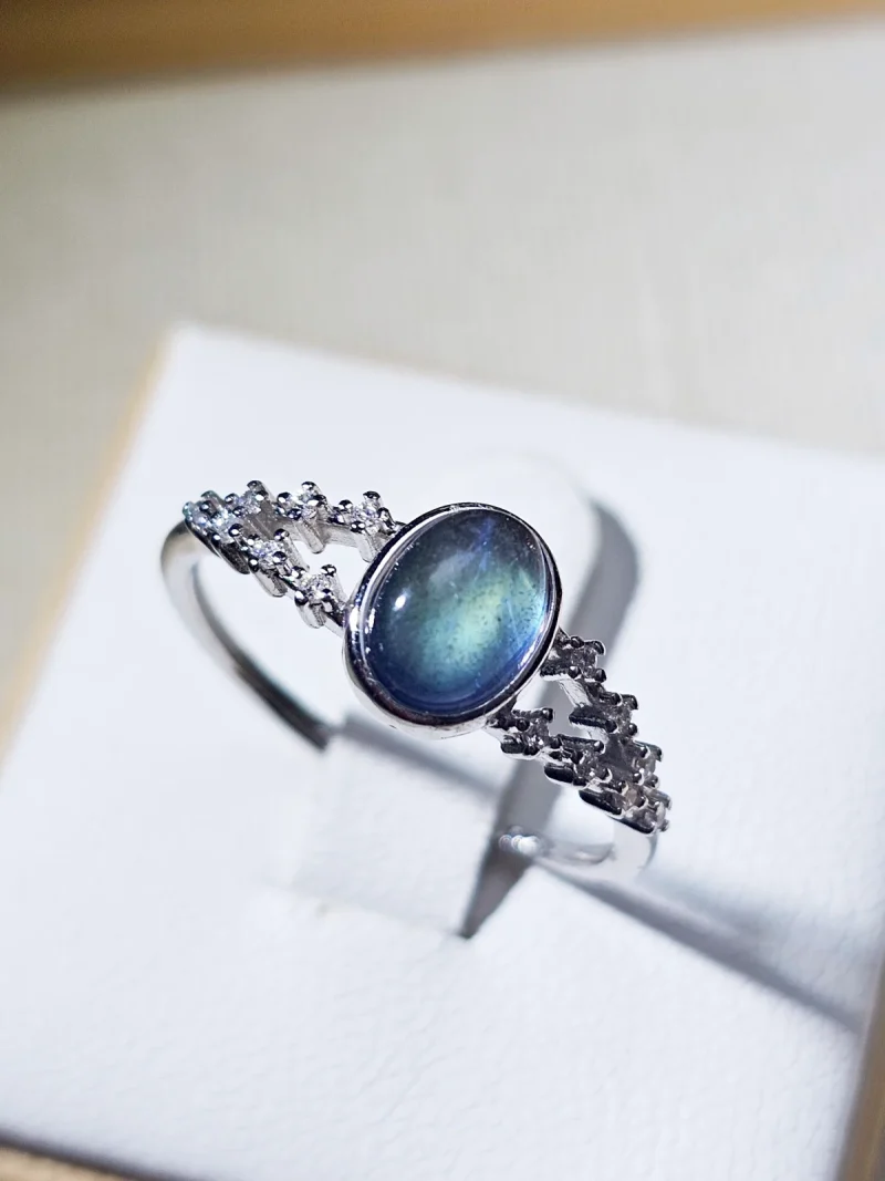 DR-SIL-03-01 Silberring mit ovalem, blau schimmerndem Mondstein und filigraner Ringschiene, verziert mit funkelnden Zirkonia-Steinen.
