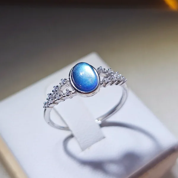 DR-SIL-03-03 Silberring mit ovalem, blau schimmerndem Mondstein und filigraner Ringschiene, verziert mit funkelnden Zirkonia-Steinen.