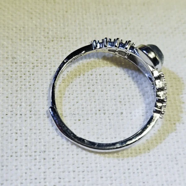 DR-SIL-03-04 Seitenansicht eines silberfarbenen Rings mit ovalem Mondstein und filigranen Zirkonia-Verzierungen an der Ringschiene.