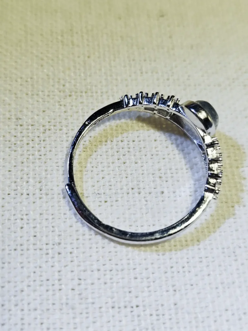 DR-SIL-03-04 Seitenansicht eines silberfarbenen Rings mit ovalem Mondstein und filigranen Zirkonia-Verzierungen an der Ringschiene.