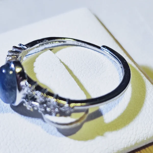 DR-SIL-03-05 Seitenansicht eines silberfarbenen Rings mit ovalem Mondstein und filigranen Zirkonia-Verzierungen an der Ringschiene.