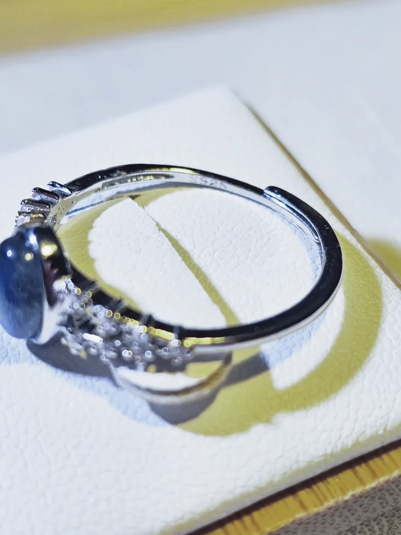 DR-SIL-03-05 Seitenansicht eines silberfarbenen Rings mit ovalem Mondstein und filigranen Zirkonia-Verzierungen an der Ringschiene.