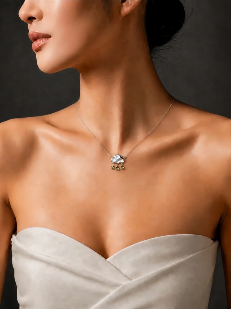 HK-SIL-03-7 Elegante Wolken-Halskette aus S925 Sterling Silber mit einer Wolke aus echtem Perlmutt und drei Peridot-Tropfen, getragen von einem Model zu einem schulterfreien cremefarbenen Oberteil vor dunklem Hintergrund.