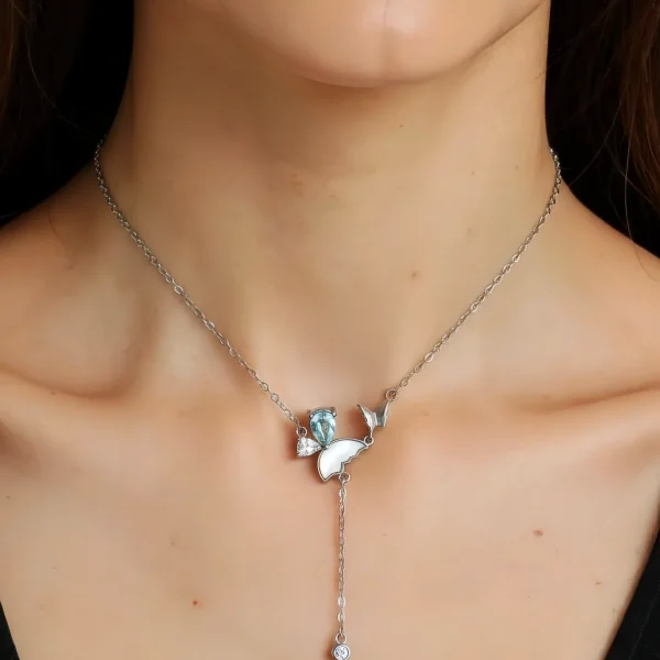 Eine Damen trägt die S925 Silber Y-Halskette mit natürlichem blauem Topas und Zirkonia Anhänge, in Schmetterling Design.