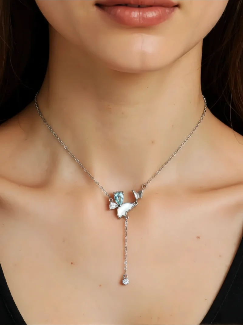 Eine Damen trägt die S925 Silber Y-Halskette mit natürlichem blauem Topas und Zirkonia Anhänge, in Schmetterling Design.
