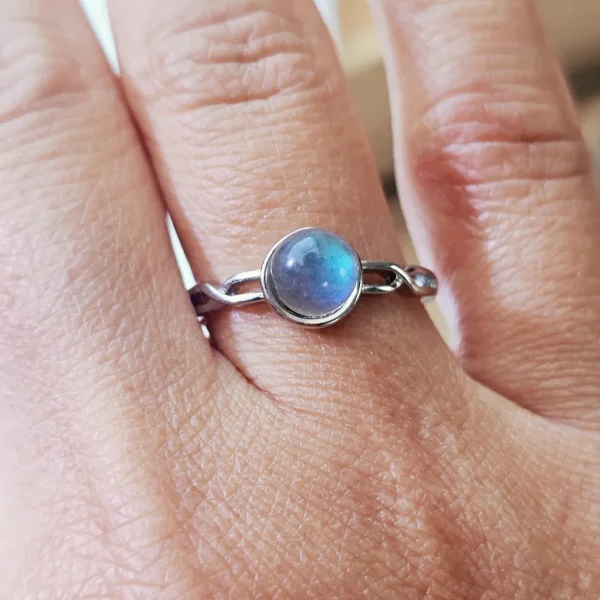DR-TDS-09-06 Filigraner Silberring mit rundem, intensiv blau schimmerndem Mondstein, am Finger getragen.